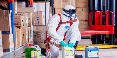 Professional in hazmat suit performing specialized soft services.