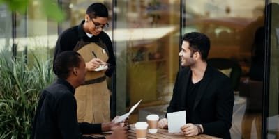 Waiter taking order from two clients at an outdoor cafe.